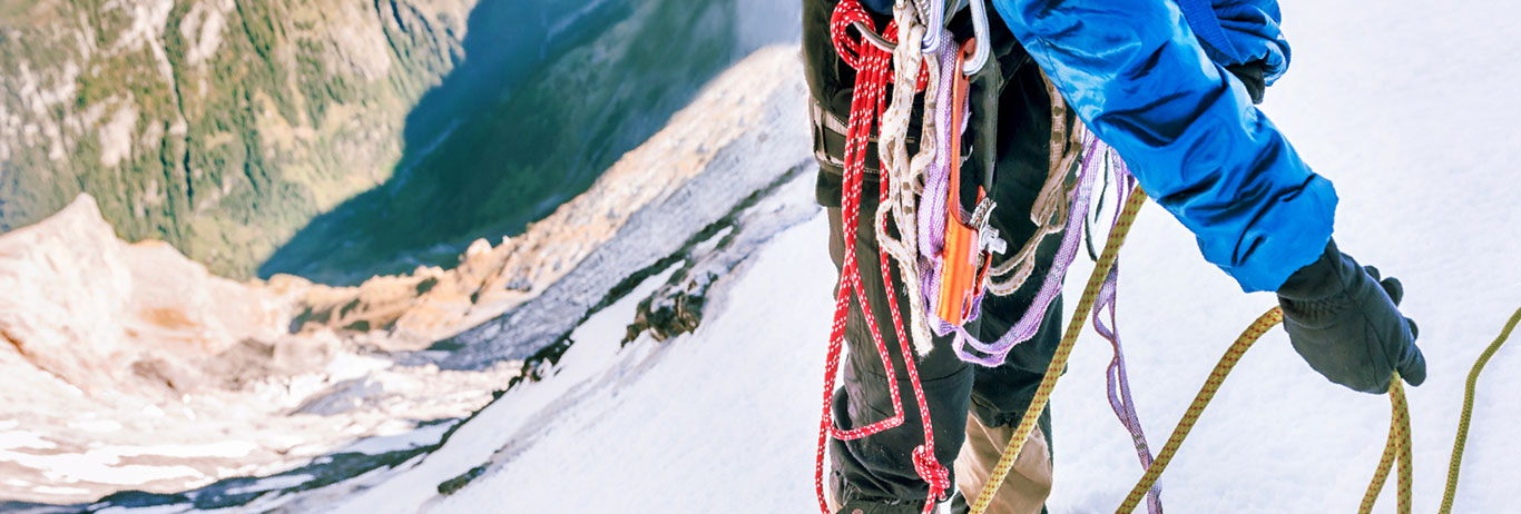 Un escalador de montaña con equipo de escalada. Con QAI alcance las metas de certificación orgánica que busca.