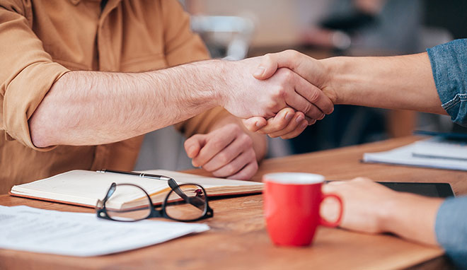 Dos personas de negocios estrechando sus manos. QAI cuenta con muchas alianzas en la industria orgánica.