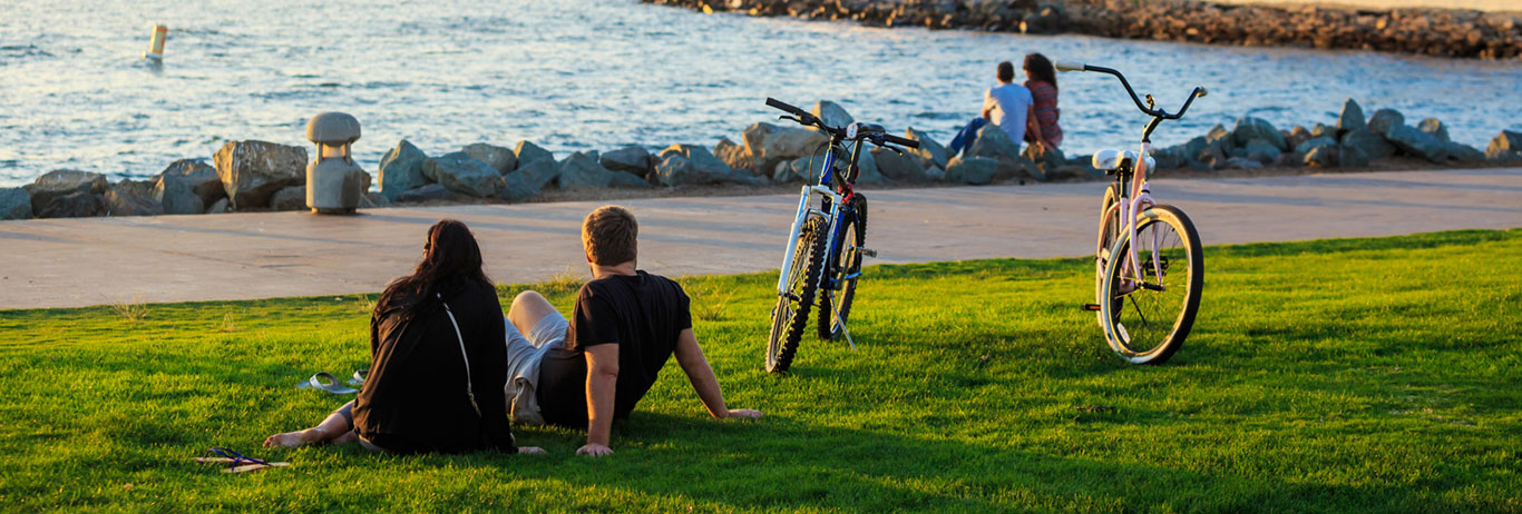 People sitting on the lawn gazing out on a lake.